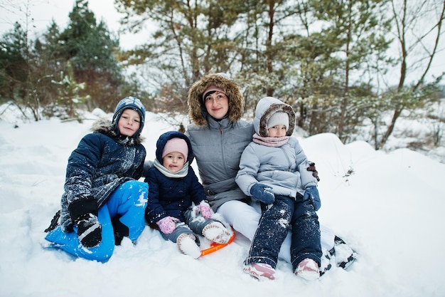 冬の自然の中で3人の子供を持つ母。雪の中で屋外。