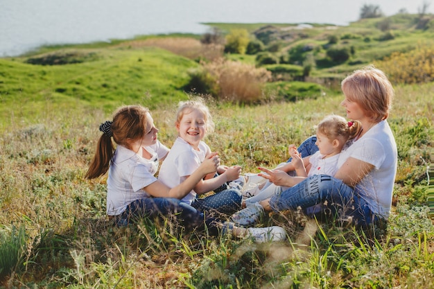 夏の芝生に座っている3人の娘を持つ母