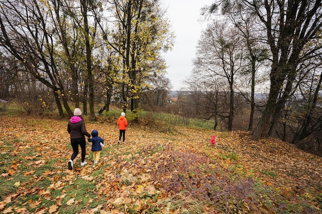 Mother with three kids walking at autumn forest