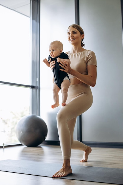 Mother with toddler daughter exercising on yoga mat