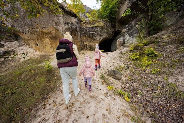 Mother with two daughters explore limestone stone cave at mountain in Pidkamin Ukraine