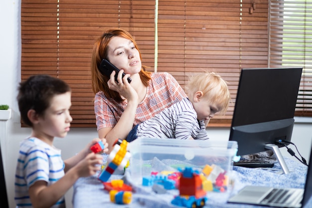 Mother with two little boys on his knees tries to laugh at home .