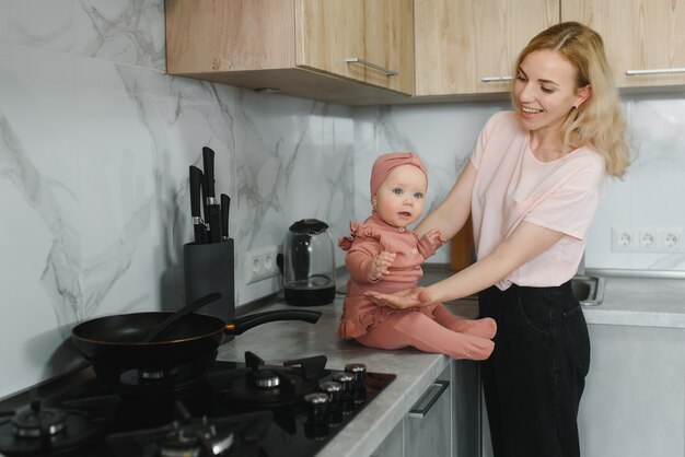 赤ちゃんを持つ女性の母親は、ストーブの上の鍋で食べ物を調理します