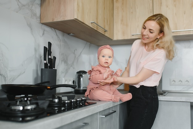 The mother of a woman with a baby cooks the food in a pot on the stove