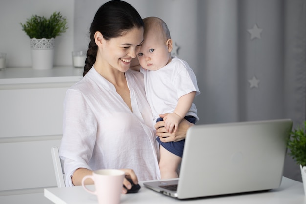 Mother working next to her baby son