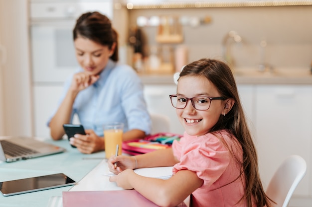 Mother works from home due to coronavirus while her daughter does her homework.