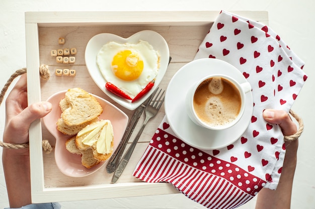 母の日の朝食。トレイには一杯のコーヒーがありますスクランブルエッグとハート型のパンの2つのプレートと私はあなたを愛している碑文お母さんが上から見る