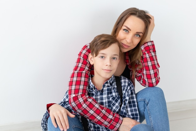 Mothers day, children and family concept - cute teen boy with his young mother at home