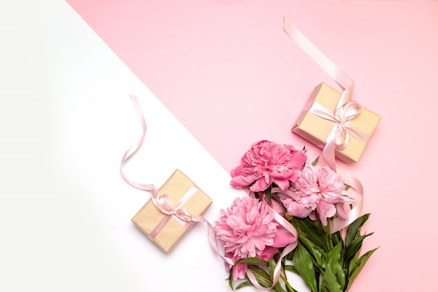 Mothers Day. Festive concept of peonies and gifts on white and pink 