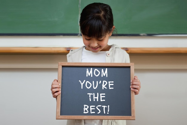 Mothers day greeting against cute pupil showing chalkboard