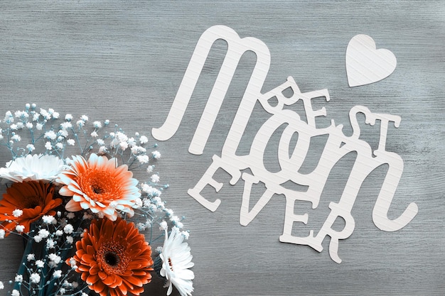 Mothers day greeting card design. Gerberas and white baby breath flowers on wood background. Flower arrangement, floral composition. Paper text Best Mom Ever. Happy Mother's day. Monochrome image.