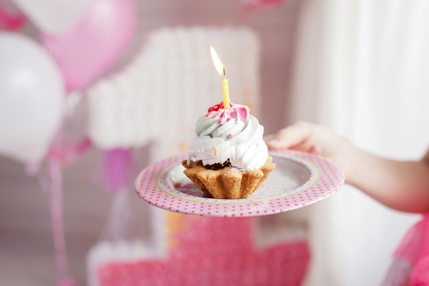 Mothers hand holding the first birthday cake whith one candle