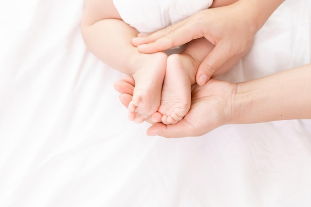 Photo mothers hand holding newborn babys barefoot