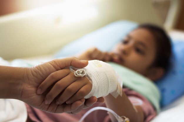 Foto la mano della madre tiene la mano della figlia nell'ospedale, il concetto sanitario e medico.