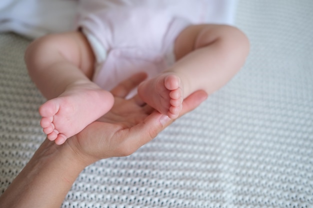 Foto le mani delle madri tengono le dita dei piedi del bambino. famiglia felice. godetevi il tempo insieme a casa. rallentatore. amore. dolce. tenerezza.