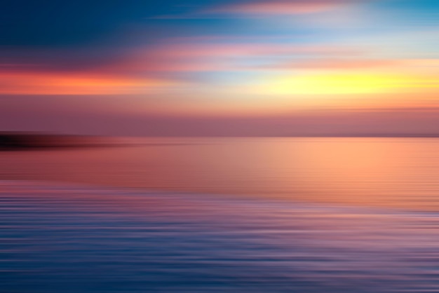 Motion blurred background of refraction in water. Panoramic dramatic view of Infinity sunset on the sea at twilight times.