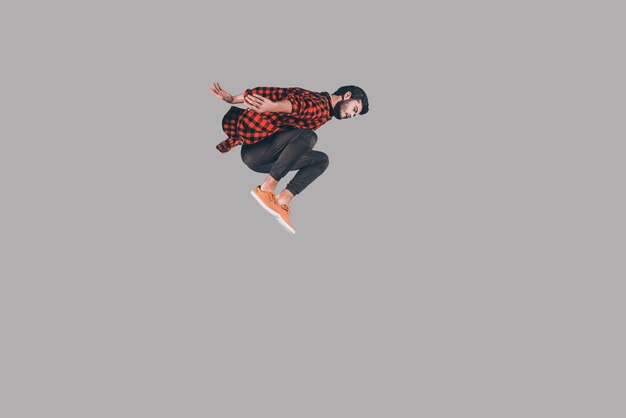 In motion. Mid-air shot of handsome young man jumping and gesturing against background