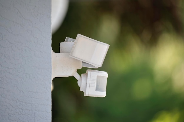 Motion sensor with light detector mounted on exterior wall of private house as part of security system