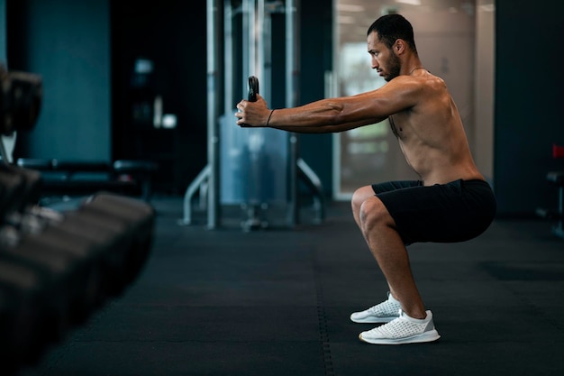 motivated athletic black man exercising with kettlebell at modern gym interior