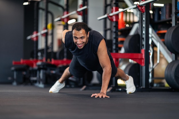 Atleta maschio nero motivato che fa esercizio di push up da un lato