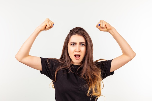 Motivated lady raised her fists and standing on white background