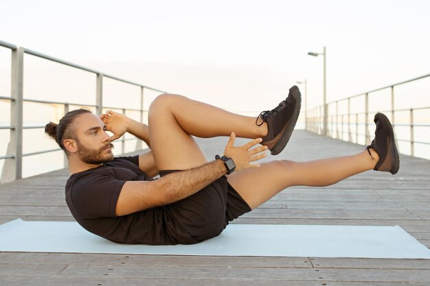 Motivated man in activewear works on abs doing bicycle crunches