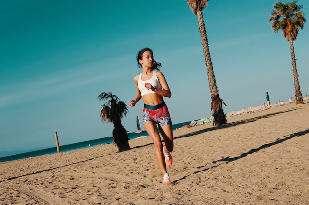 Мотивация формировать свое тело. Полная длина красивой молодой женщины в спортивной одежде, бегающей трусцой во время тренировки на открытом воздухе