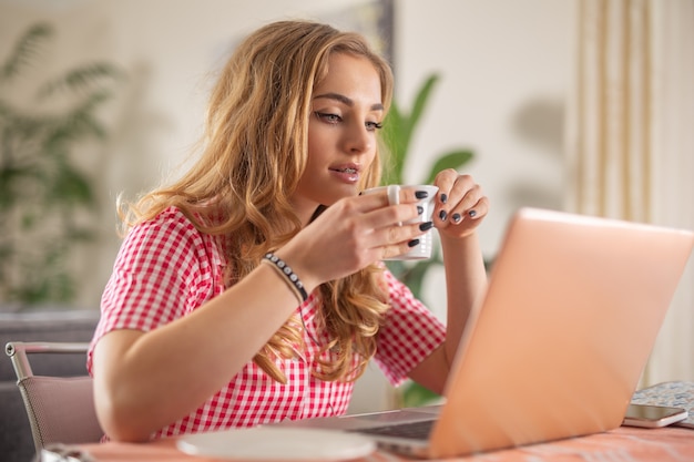 동기 부여된 성공적인 관리자는 노트북을 통해 온라인으로 물건을 만들고 즐거운 커피를 마십니다.