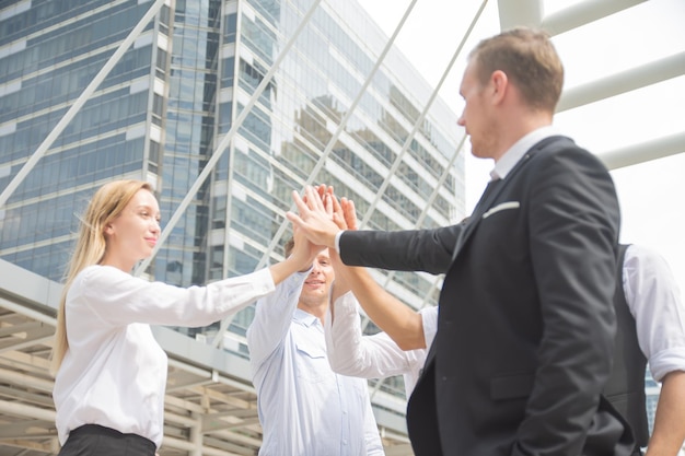 Motivated young business team pledging support raising their hands into a pyramid