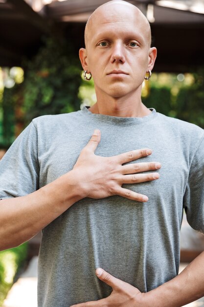 Photo motivated young fitness man doing breathing exercises while standing outdoors