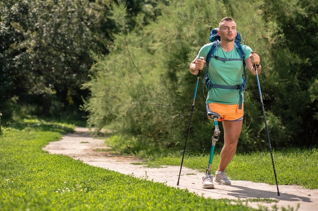 Motivated young man suffering from paralysis while trying Nordic walking