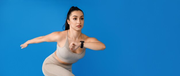 Motivated young sportswoman running over blue background