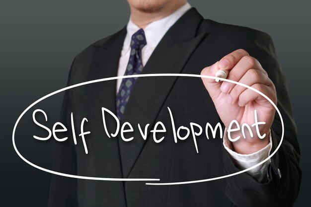 Photo motivational business concept image of a businessman holding marker and write self development words