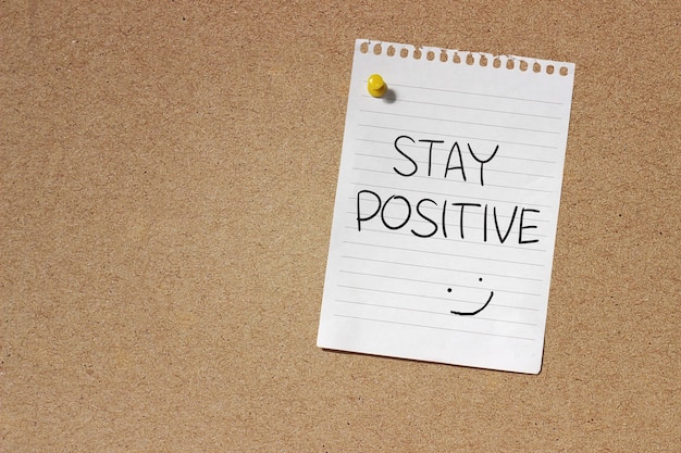 Photo motivational concept image of message note paper pinned on cork board with stay positive