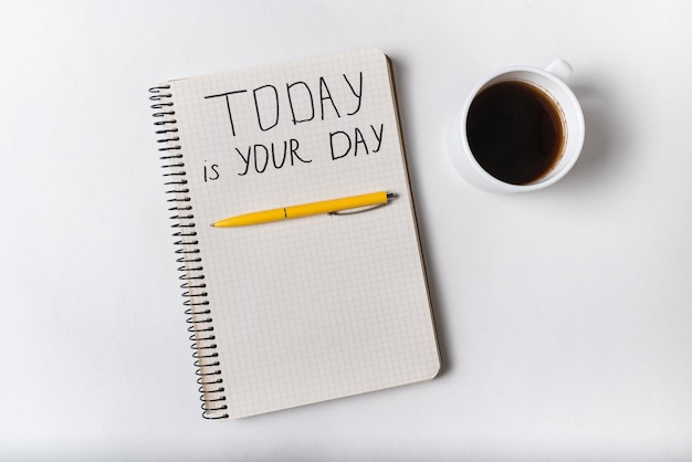 Motivational inscription in notepad TODAY IS YOUR DAY. Coffee, notebooks and pen. Handwriting