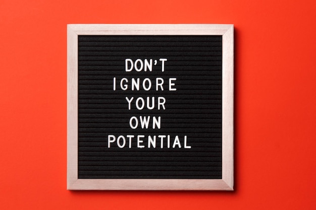 Motivational quote on black letter board on orange background Don't ignore your own potential Inspirational quote of the day