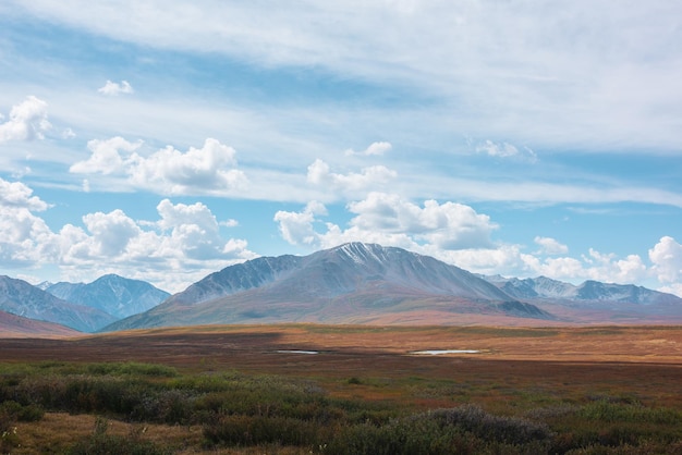 Photo motley autumn landscape with sunlit high mountain plateau with lakes and beautiful mountain top under dramatic cloudy sky vivid autumn colors in mountains shadows of clouds in changeable weather