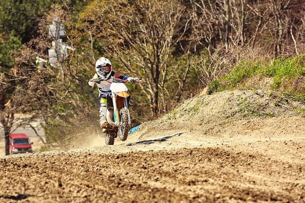 バイクを加速するモトクロスドライバーが離陸し、レーストラックのスプリングボードにジャンプします。