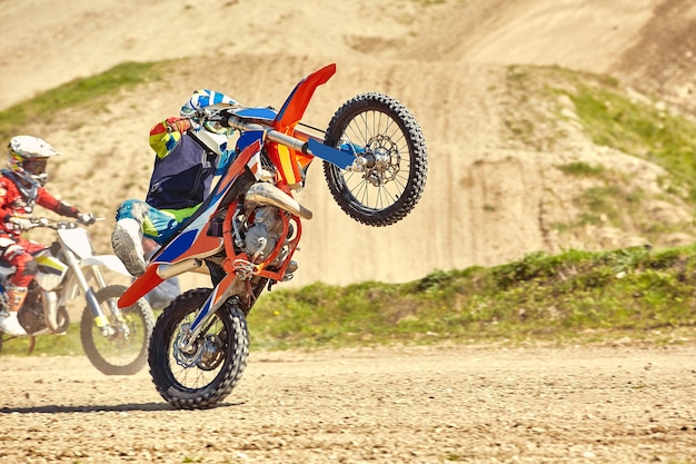 Pilota di motocross in azione che accelera la moto decolla e salta sul trampolino di lancio in pista