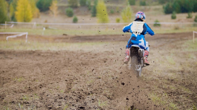 Motocross racer starting on dirt Cross MX bike - pieces of dirt flying - de-focused, telephoto