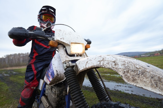 Photo motocross racing in the countryside with professional biker against cloudy sky