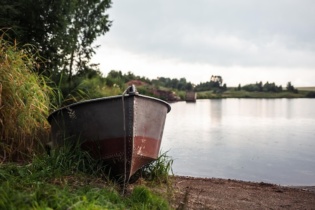 A motor boat is parked at shore of a lake or river in the evening at sunset or early in the morning