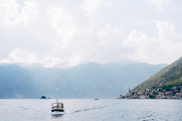 Motor boat sails along the kotor bay against the backdrop of the town of perast montenegro