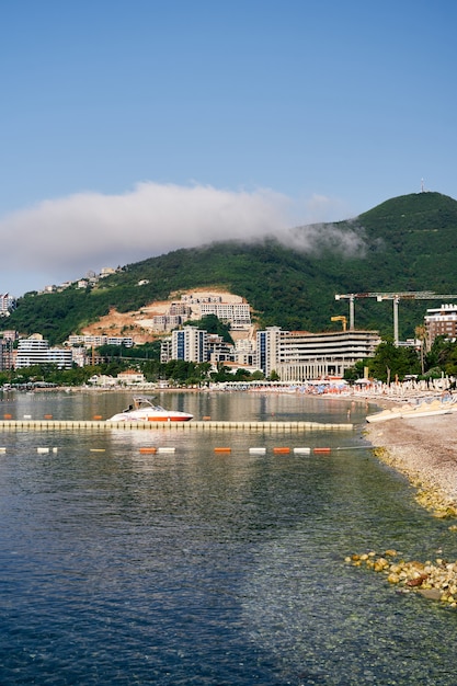 Motor boat stands near the pier against the backdrop of houses and greenery