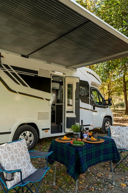 Motor home with a table and chairs set up outside the vehicle and ready to eating and drinking