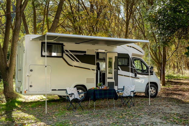 Motor home with a table and chairs set up outside the vehicle and ready to eating and drinking