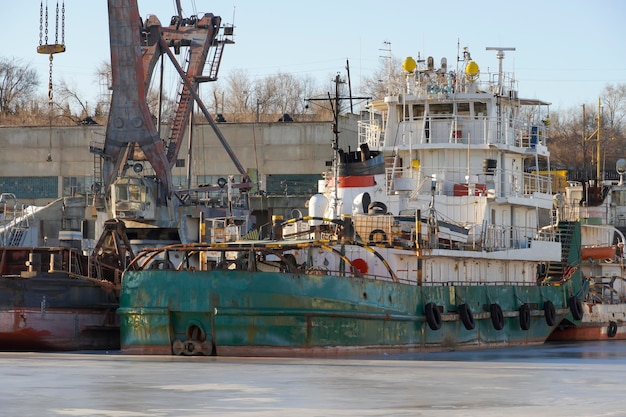 Rimorchiatore di spinta della nave a motore in vernice verde al parcheggio di inverno nell'acqua stagnante del fiume volga