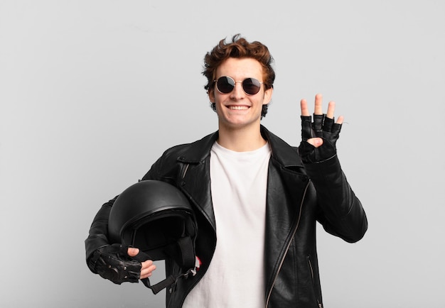 Motorbike rider boy smiling and looking friendly, showing number four or fourth with hand forward, counting down