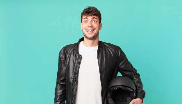 Motorbike rider looking happy and pleasantly surprised, excited with a fascinated and shocked expression