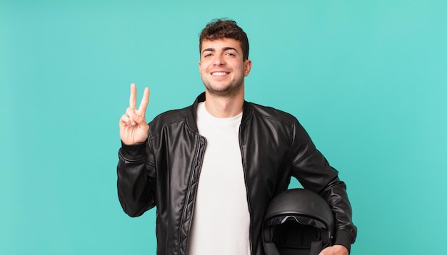 Motociclista sorridente e dall'aspetto amichevole, mostrando il numero due o il secondo con la mano in avanti, conto alla rovescia